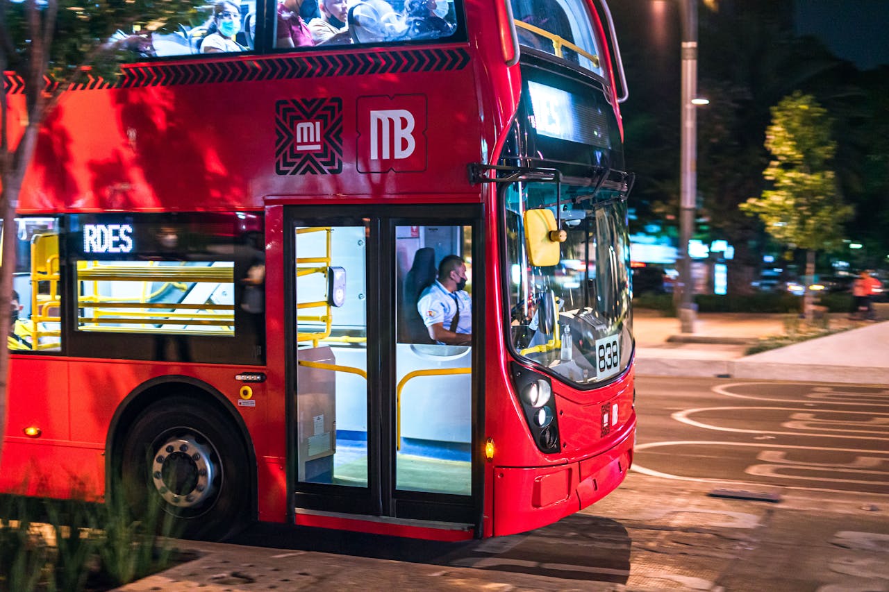 A vibrant red city bus transporting passengers at night in Ciudad de México.