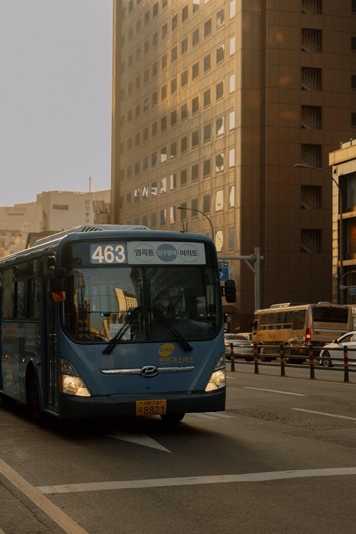 Blue city bus on busy urban street with skyscrapers in the background, showcasing city transport.