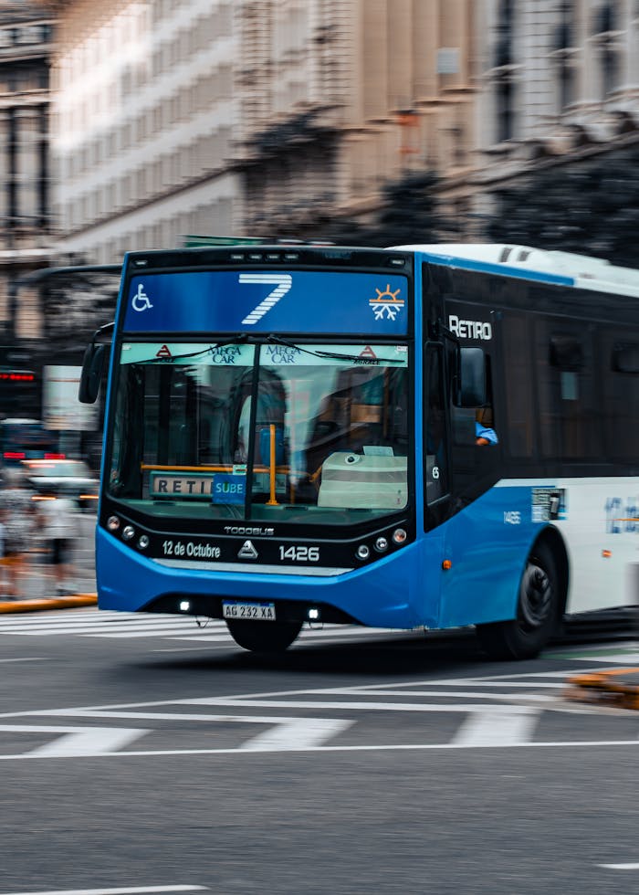 Blue public bus number 7 traveling on an urban street, representing city transportation.